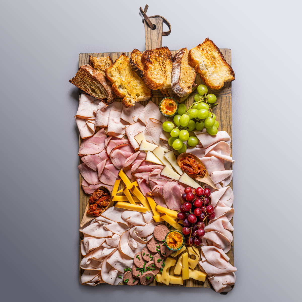 tabla de pavo y quesos gourmet sobre base de madera para eventos en Bogotátabla con pechuga de pavo, pastrami, quesos ibérico y emmental, hummus y focaccia