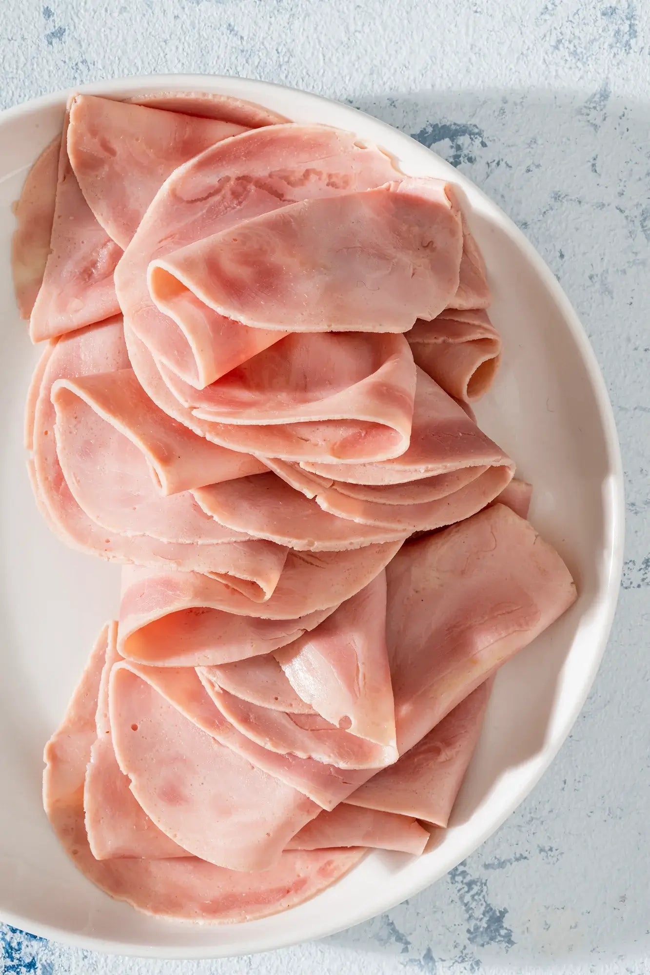 Jamón de Pavo en rodajas, preparado con muslos de pavo cocinados al vapor en sus jugos, en un plato.