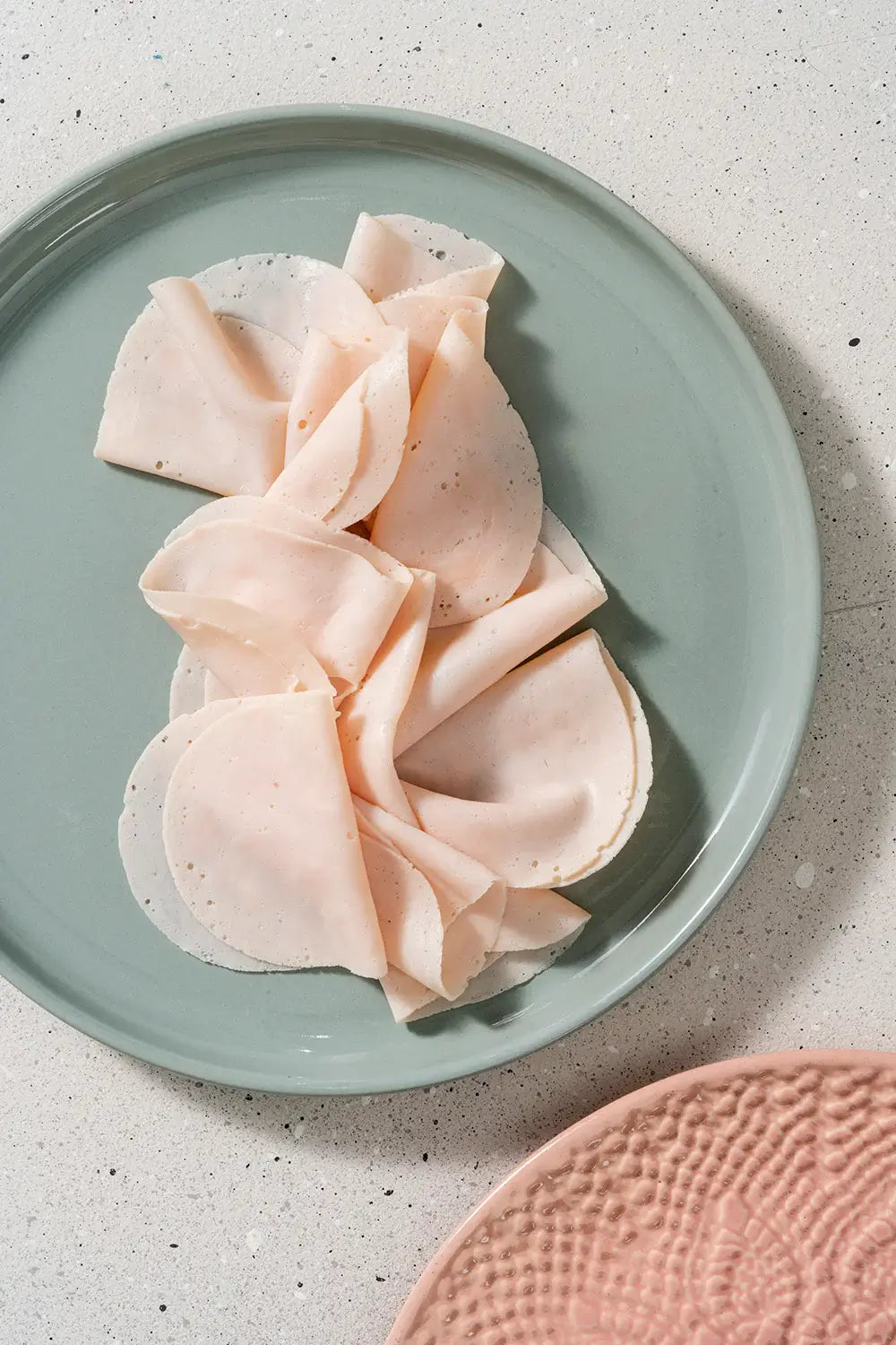 Pechuga de Pavo en rodajas sobre un plato de color verde, lista para servir y disfrutar.