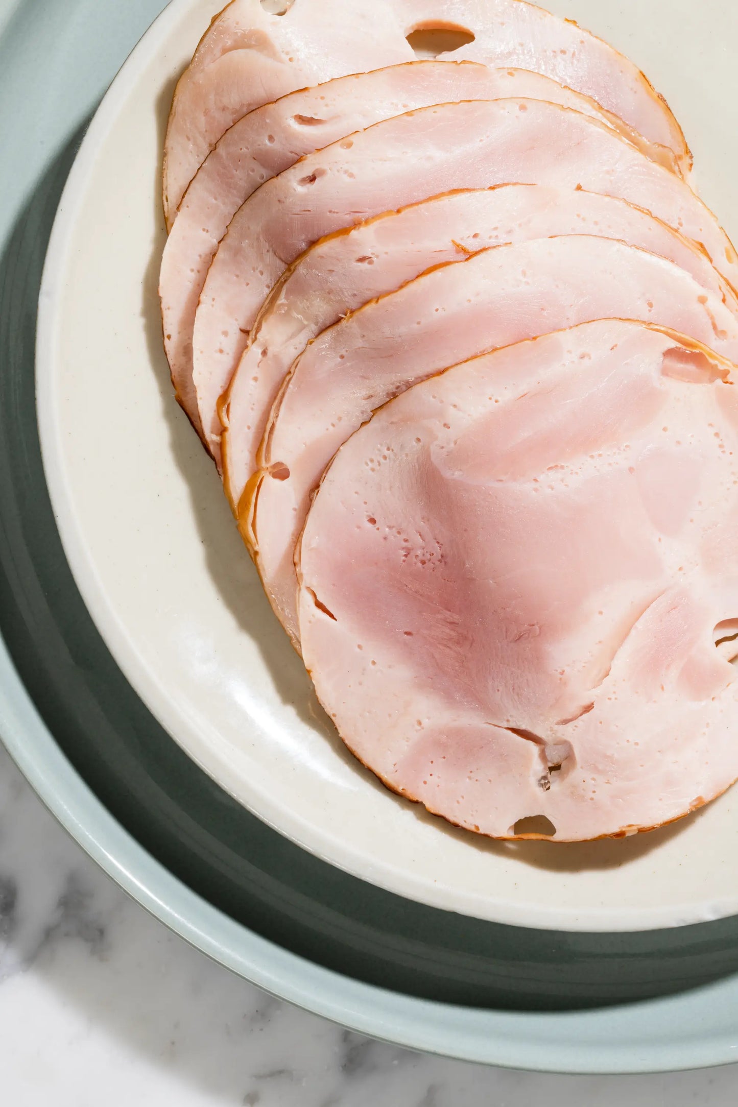 Rollo de Pavo Ahumado, lonchas de pavo en un plato, mostrando la textura y el color característico del producto.