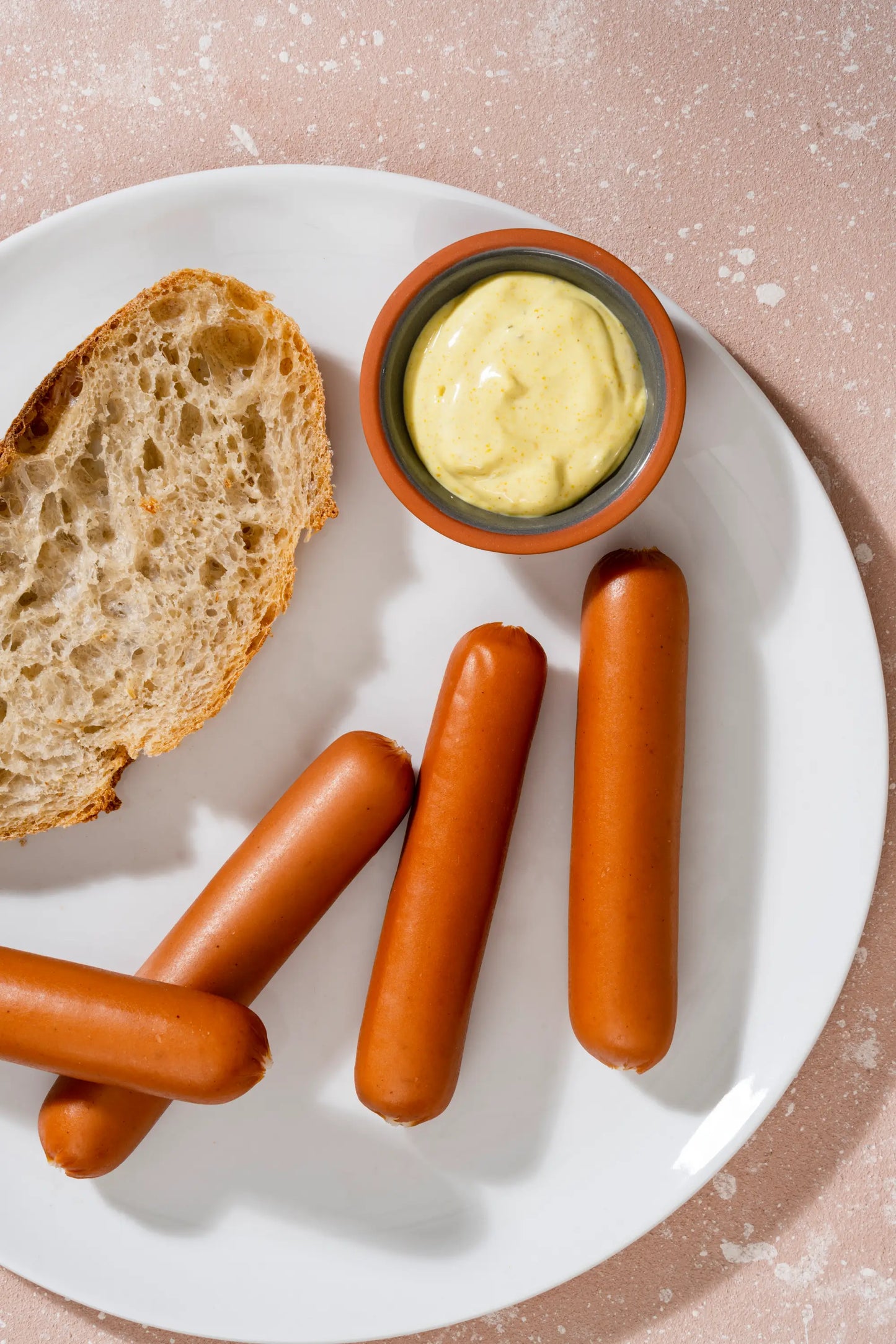 Salchichas de Pavo en un plato con pan y mostaza, producto artesanal de Delipavo.