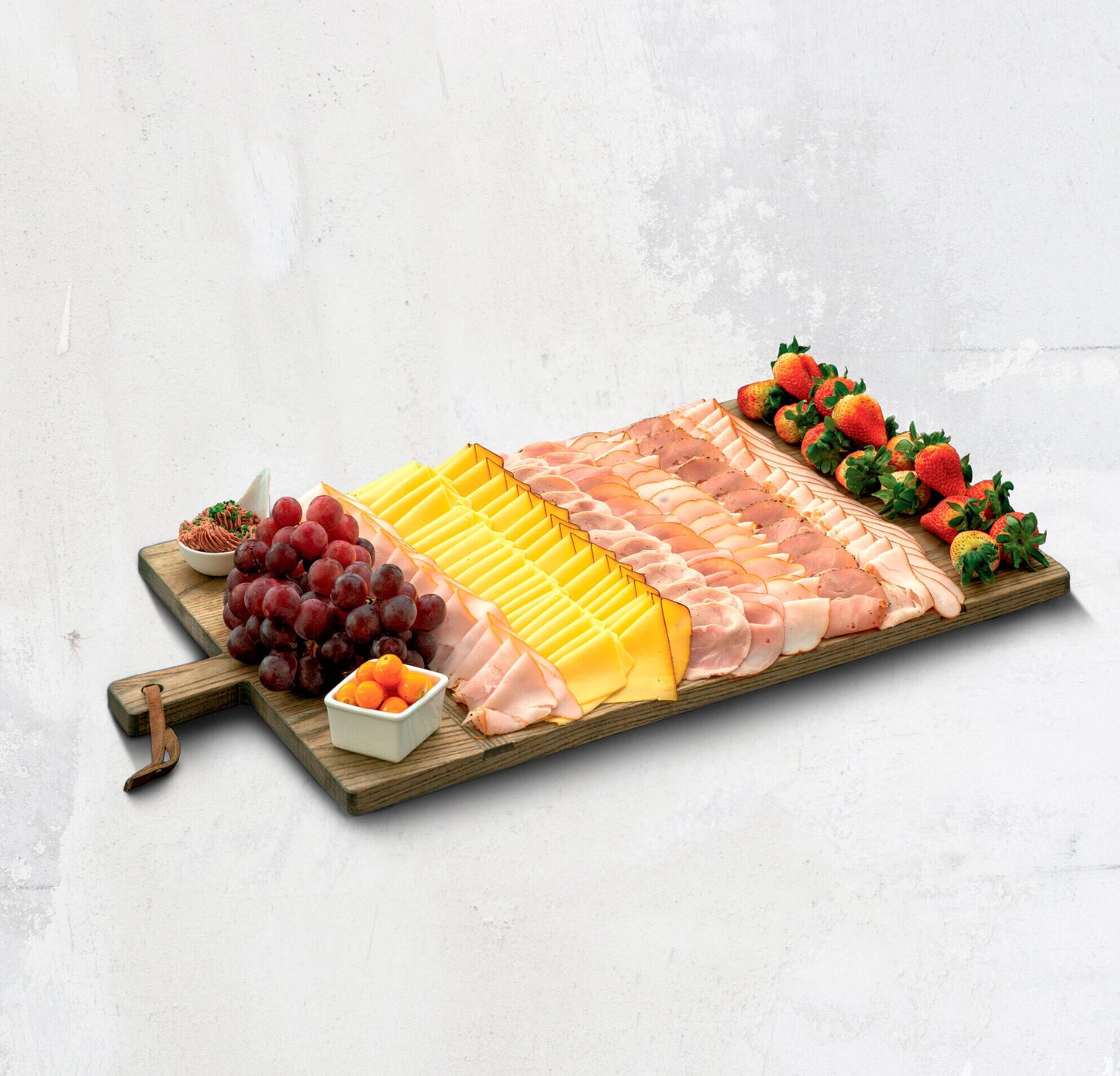 tabla de pavo ahumado balance ideal con jamón de pavo miel y mostaza, quesos, uvas y fresas sobre base de madera